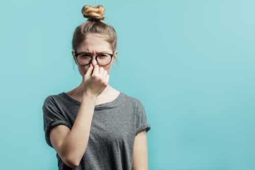 Une femme se tient le nez et est répugnée