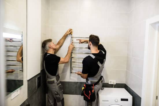 plombier le havre - Deux plombiers installent un radiateur