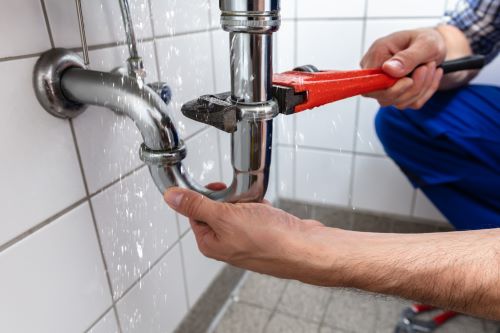 plombier Saint Forget - un homme ouvre un siphon avec une clé de serrage