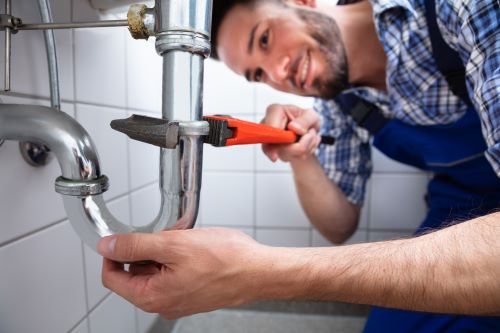 plombier les Loges-en-Josas - un artisan souriant resserre un siphon