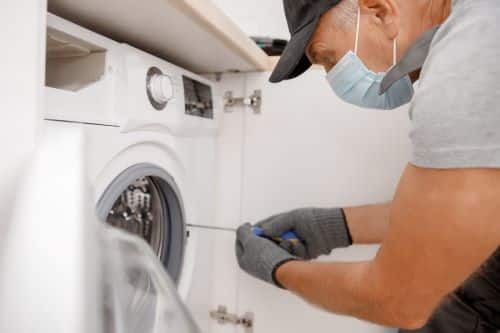 plombier Colombes - un artisan installe une machine à laver