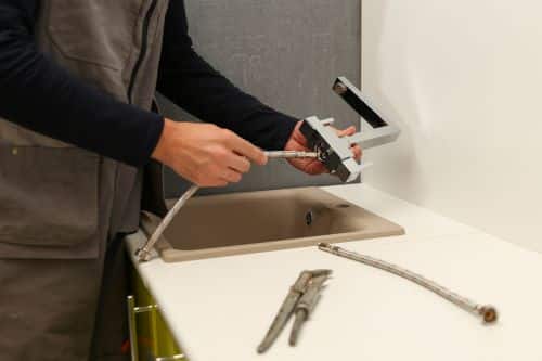 Plombier Grasse - Un plombier installe un robinet de cuisine.