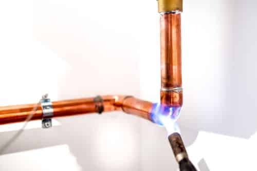 plombier Suresnes - un artisan installe un circuit de plomberie en cuivre