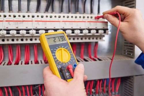 Électricien Angers - Un artisan mesure le courant sur circuit électrique.