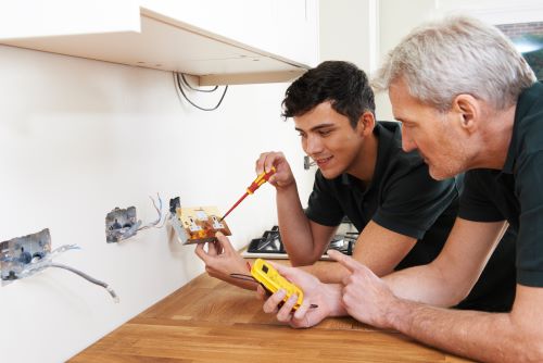 Électricien Caen - Des artisans électriciens installent des prises électriques.