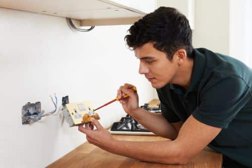 Électricien Clermont-Ferrand - Un artisan installes des prises électriques dans une cuisine.