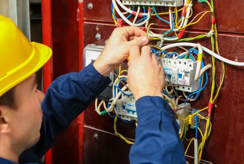 Électricien Créteil - Un électricien relie les fils dans un tableau de distribution.