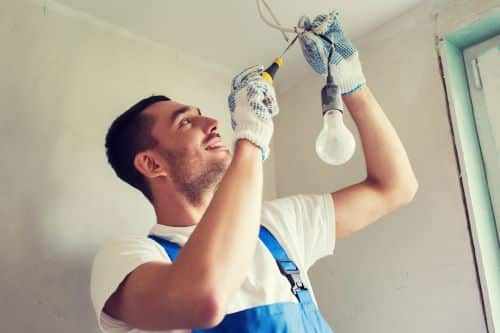 Électricien Lille - Un artisan installe des ampoules au plafond.