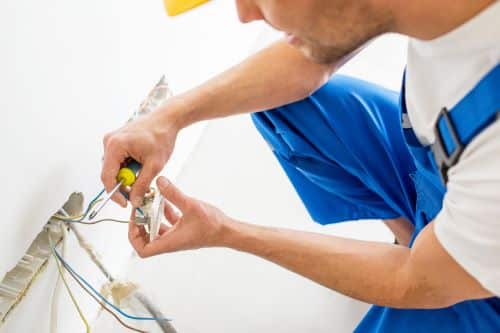 Électricien Mulhouse - Un artisan installe une prise électrique.