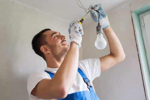 Électricien Nîmes - Un électricien installe des ampoules au plafond.