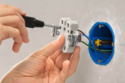 Électricien Perpignan - Un artisan installe une prise électrique.