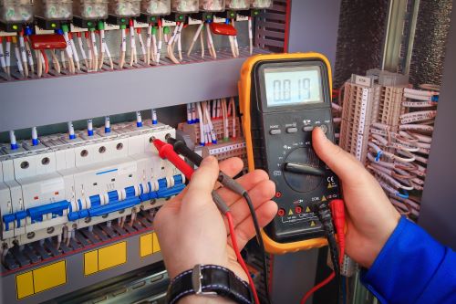 Électricien Roubaix - Un artisan effectue des mesures sur un tableau électrique.