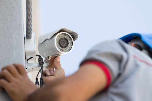Électricien Saint-Etienne - Un technicien installe une caméra de surveillance.