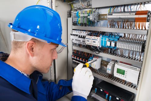 Électricien Villeurbanne - Un électricien travaille sur une boîte à fusibles.