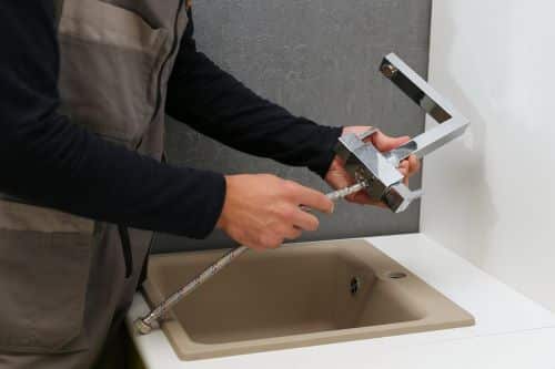 Plombier Belfort - Un plombier installe un robinet.