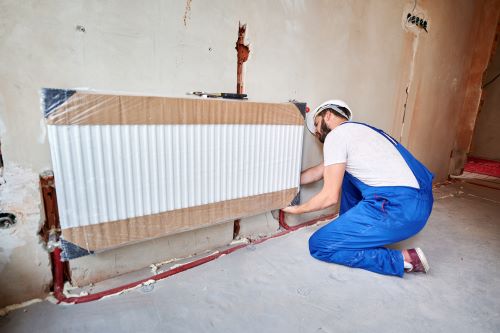 Plombier Brunoy - Un plombier chauffagiste installe un radiateur.