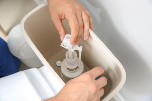 Plombier Colomiers - Un plombier répare le bac d'un toilette.