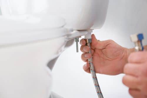 Plombier Compiègne - Plombier travaillant sur l'arrivée d'eau de toilettes.