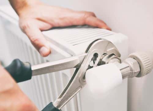 Plombier Draguignan - Un plombier répare l'arrivé d'eau d'un radiateur.