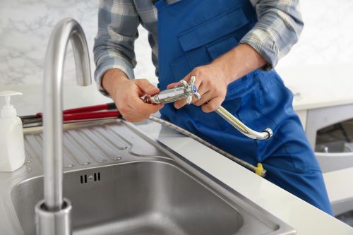 Plombier Romainville - Un plombier installe un robinet de cuisine.