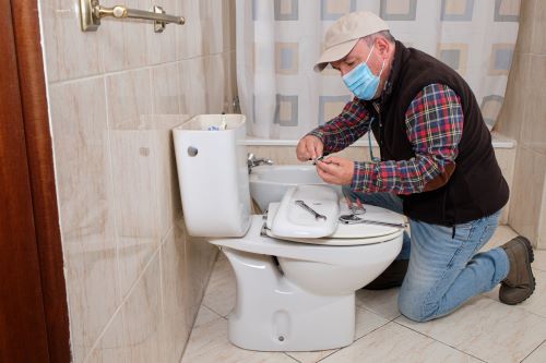 Plombier Talence - Un artisan installe des toilettes.