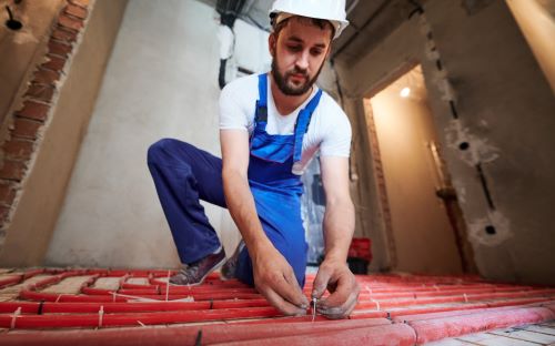 Plombier Taverny - Un artisan met en place un chauffage au sol dans une nouvelle maison.