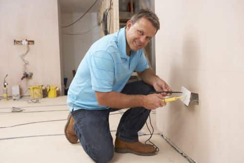 électricien Nantes - Un artisan installe un prise électrique murale.