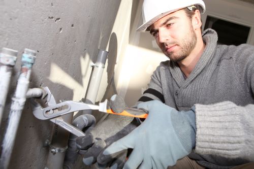 plombier Grigny - un artisan installe un circuit de plomberie dans une maison en construction