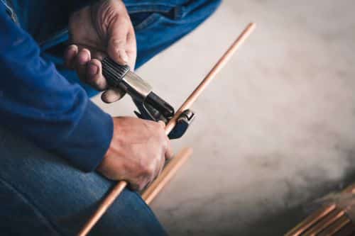 plombier L'Haÿ-les-Roses - un artisan avec un coupe-tube prépare un circuit de chauffage