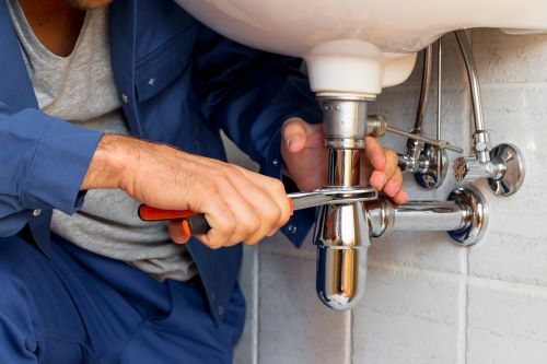 plombier L'Haÿ-les-Roses - un artisan installe un siphon sur un robinet neuf