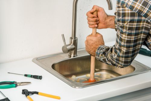 plombier Malakoff - un artisan débouche un évier avec une ventouse