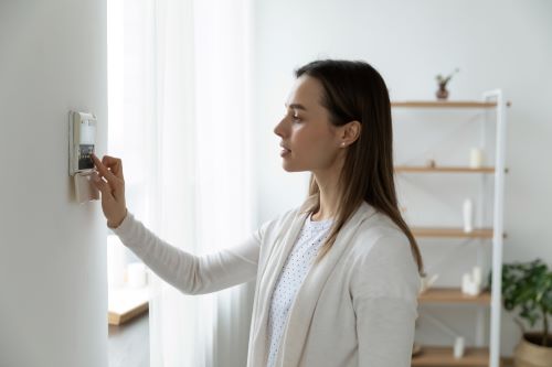 Chauffagiste Mulhouse - Une femme règle le chauffage de sa maison.