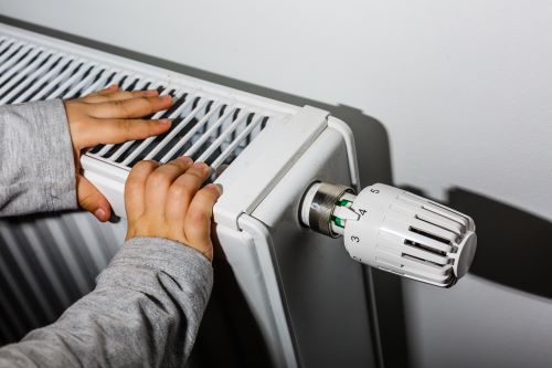 Chauffagiste Rouen - Une personne se réchauffe auprès d'un radiateur.