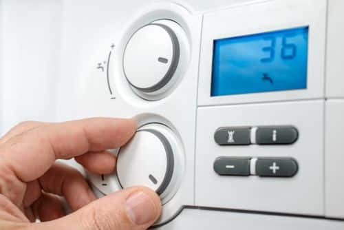 Chauffagiste Tous - Un homme règle la température de son thermostat