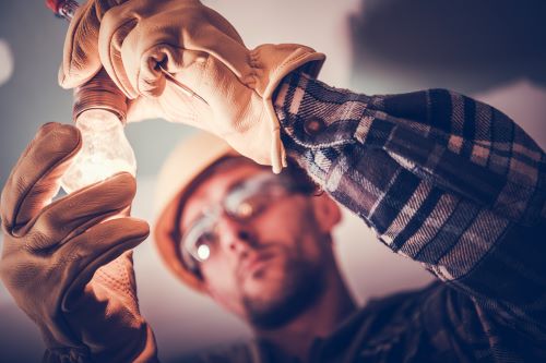 Électricien Amiens - Un artisan installe une ampoule.