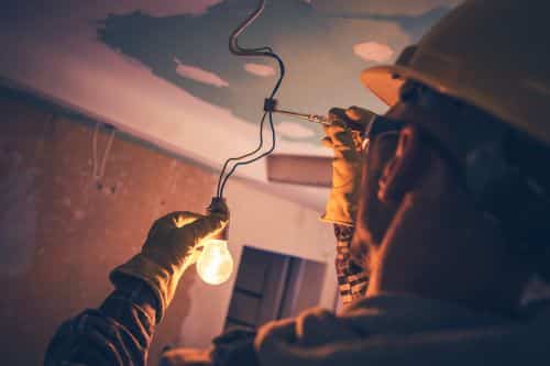 Électricien Besançon - Un artisan installe une ampoule.