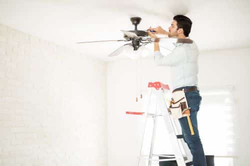 Électricien Courbevoie - Un artisan installe un ventilateur de plafond.