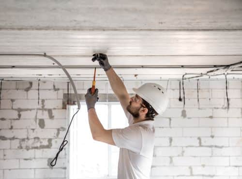 Électricien Neuilly-sur-Seine - Un artisan dispose des câbles au plafond d'une habitation en construction.