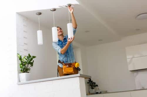 Électricien Neuilly-sur-Seine - Un artisan installe des lampes suspendues dans une cuisine.