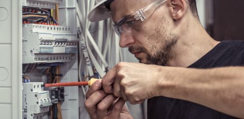 Électricien Pau - Un artisan répare un tableau électrique.