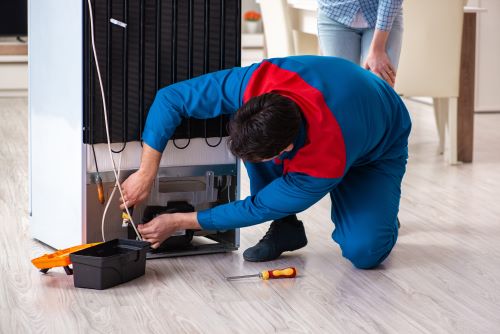 Électricien Rouen - Un électricien répare un réfrigérateur.