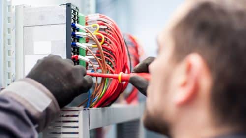 Électricien Tours - Un artisan fait des branchements sur un tableau électrique.