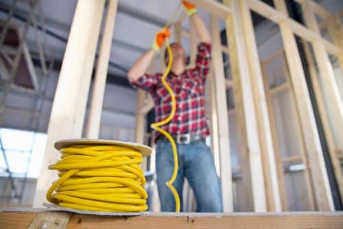 Électricien Villejuif - Un artisan dispose des câbles dans une maison en construction.