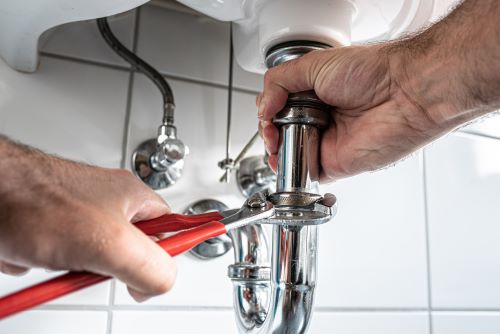 plombier Étampes - un artisan desserre le siphon d'un lavabo