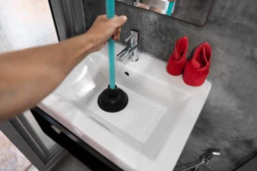 plombier Les Lilas un artisan débouche un lavabo avec une ventouse