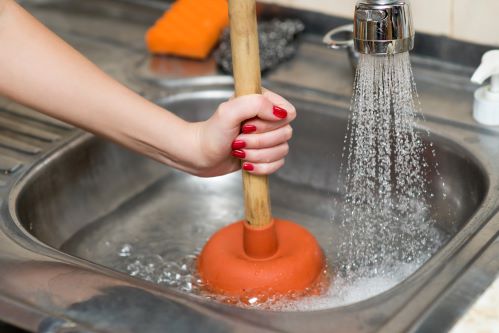 plombier Orly - une femme débouche le siphon d'un évier avec une ventouse