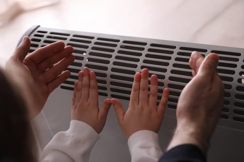Chauffagiste Alfortville - Des individus se réchauffent les mains sur un radiateur.