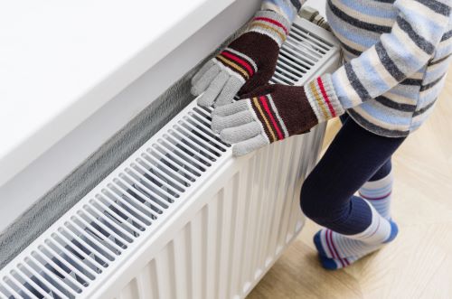 Chauffagiste Antony - Une personne se réchauffe les mains sur un radiateur.