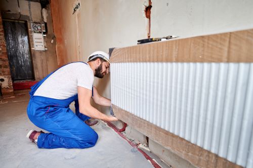 Chauffagiste Béziers - Un artisan installe un radiateur.