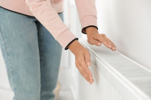 Chauffagiste Neuilly-sur-Seine - Une femme se réchauffe les mains sur un radiateur